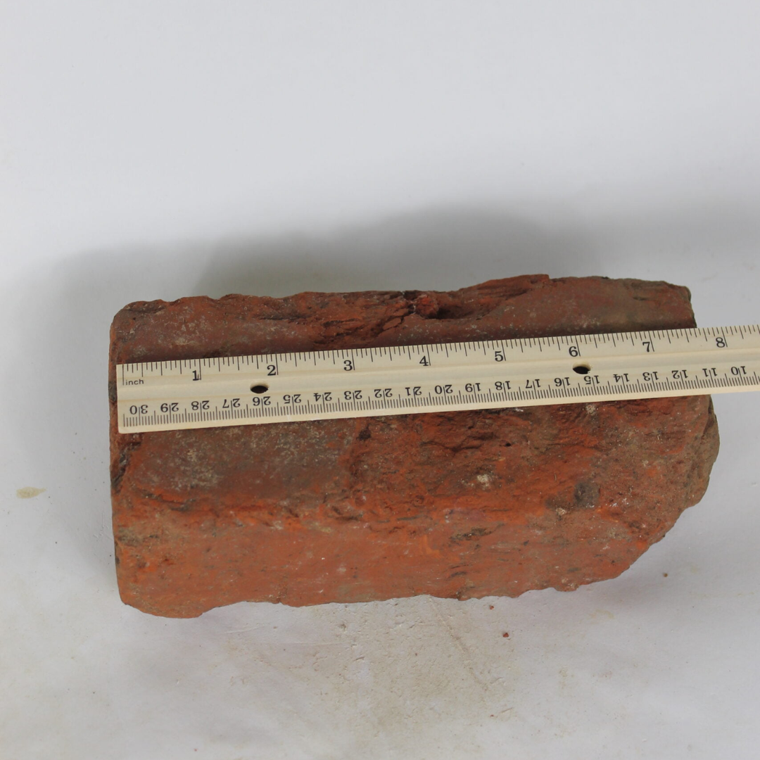 Antique brick being measured by wooden ruler