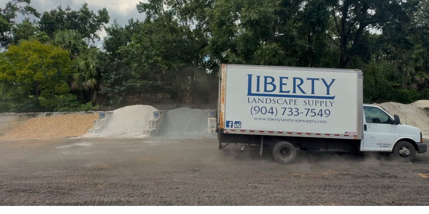 White truck with 'Liberty Landscape Supply' branding parked near a gravel area.