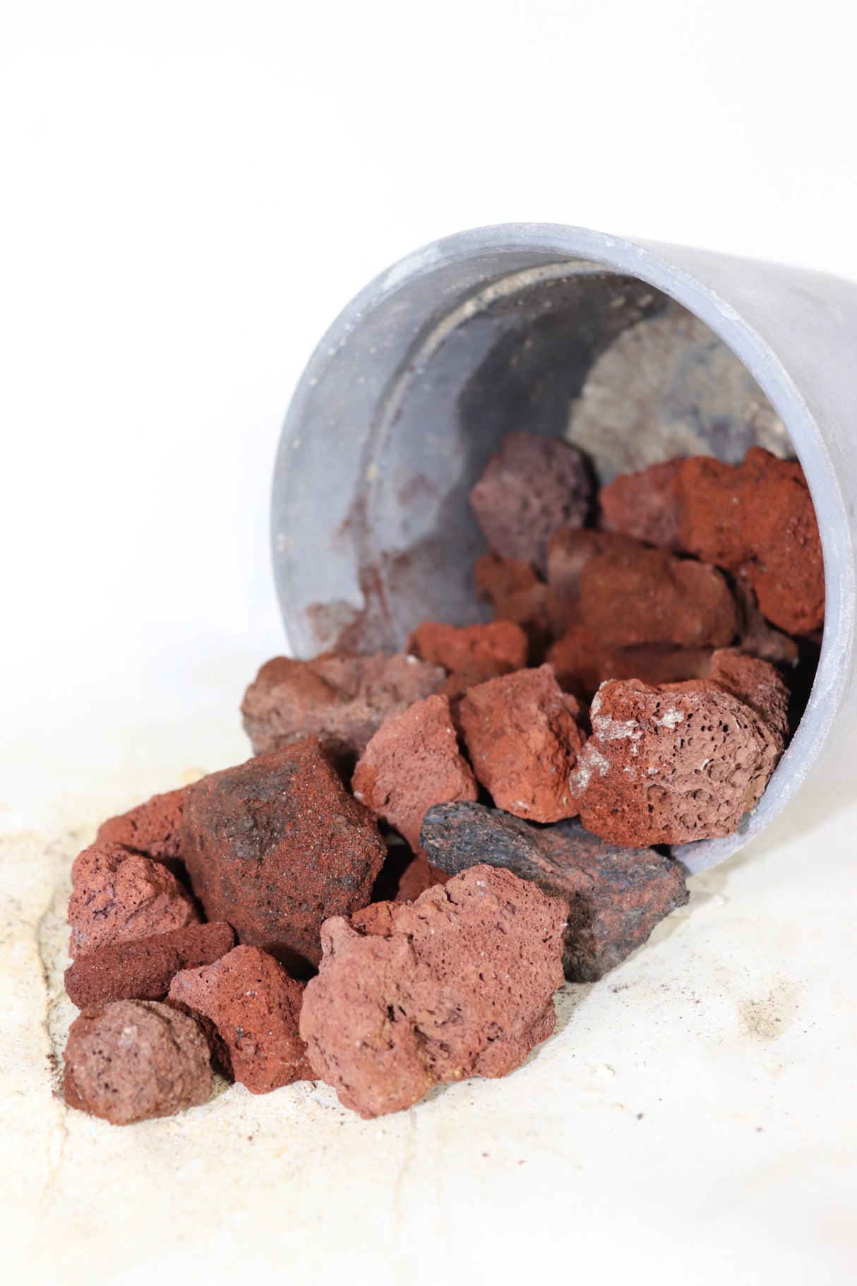 red lava rock spilling out of grey bucket