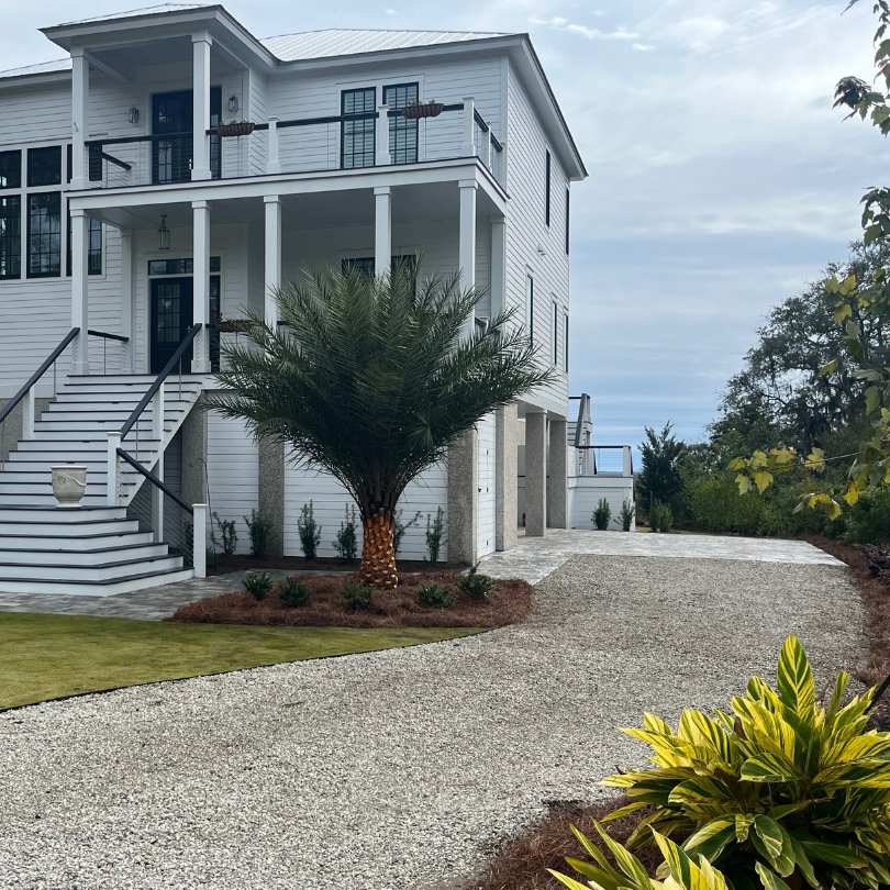 white house with a limestone driveway and fresh landscape