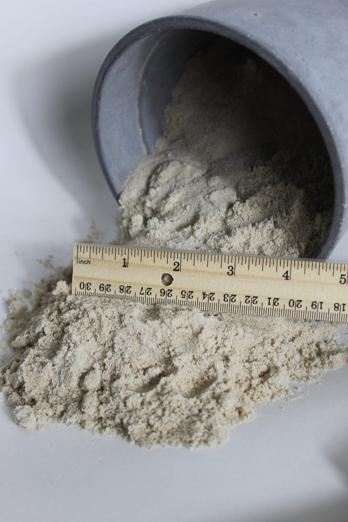 masonry sand falling out of bucket and compared to ruler for scale