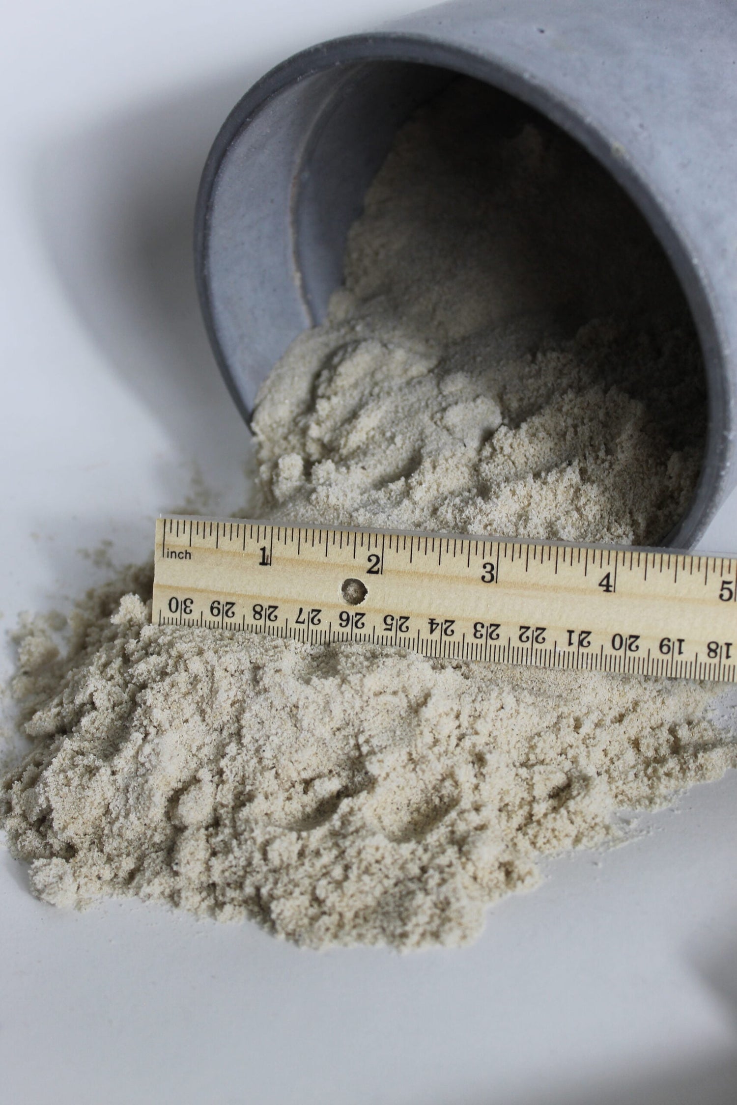masonry sand falling out of bucket and compared to ruler for scale