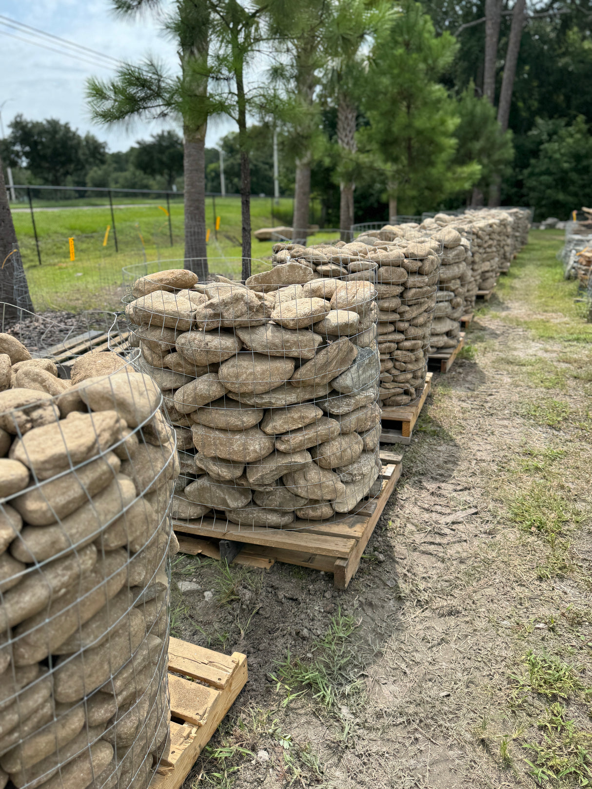 Stacks of stone on wooden pallets in an outdoor setting with trees in the background.