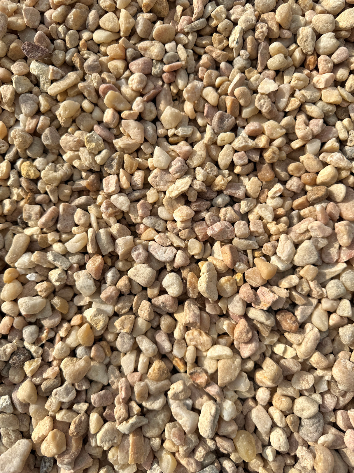 colors of pink, white, and beige make up a pile of white pea gravel