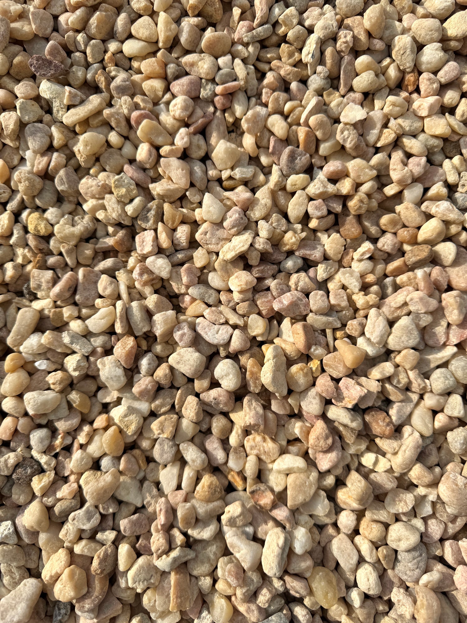 colors of pink, white, and beige make up a pile of white pea gravel