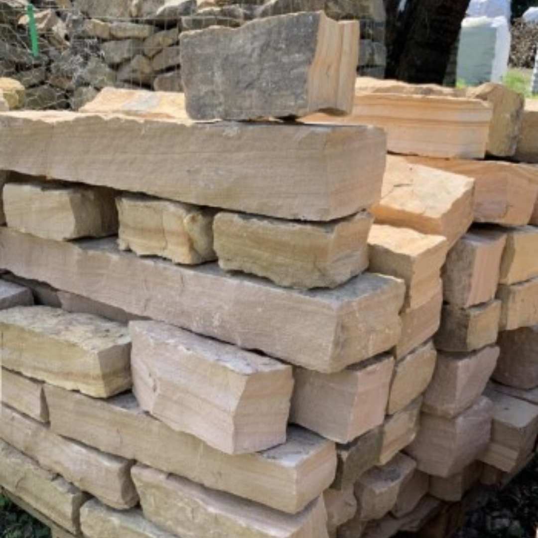 A pile of strip rubble stone blocks with tan and brown colors, stacked together.