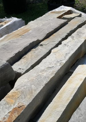 A pile of rectangular stone blocks with tan and brown colors, stacked together.