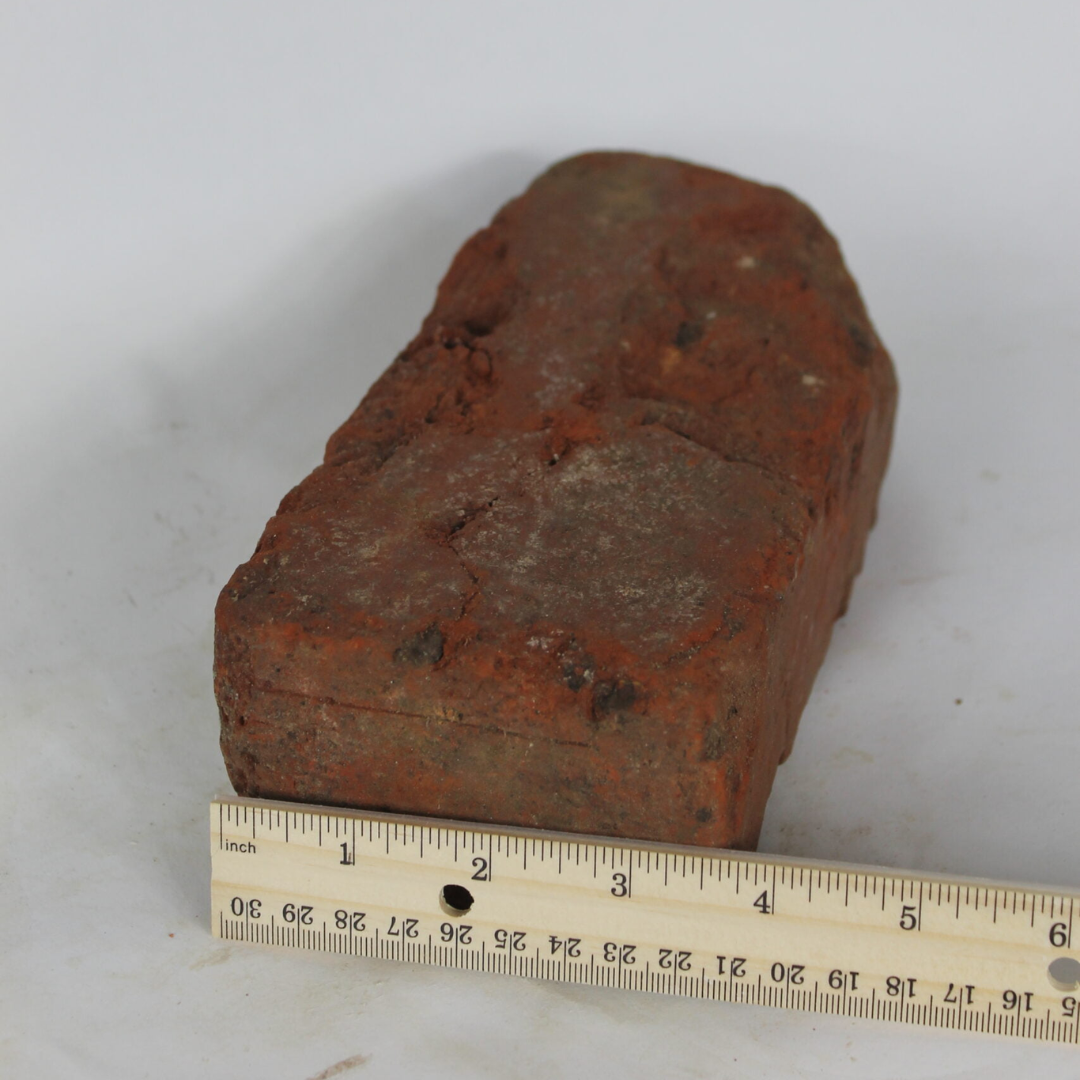 antique brick measured by wooden ruler at almost 4 inches