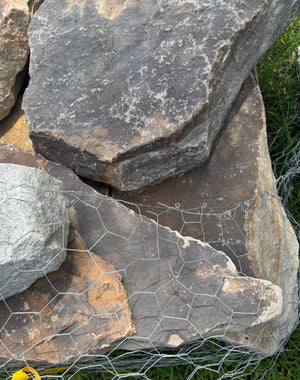 Stack of large stones with a wire mesh on a natural background
