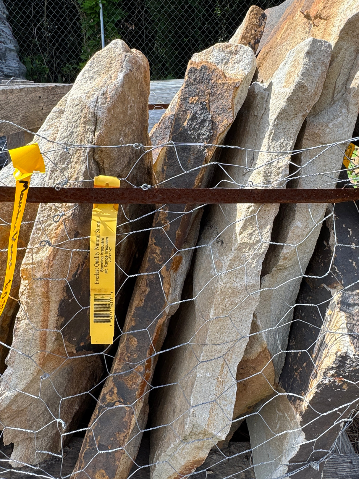 Stack of large mountain range flagstone slabs with a wire mesh and yellow tag.