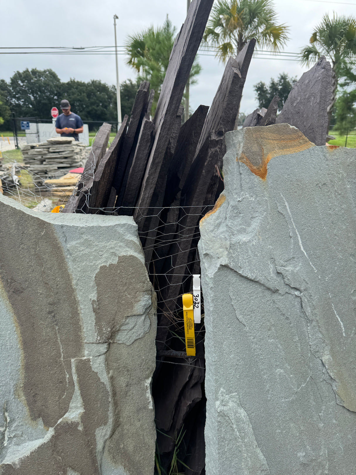 Stack of gray stone slabs with a person and vehicle in the background