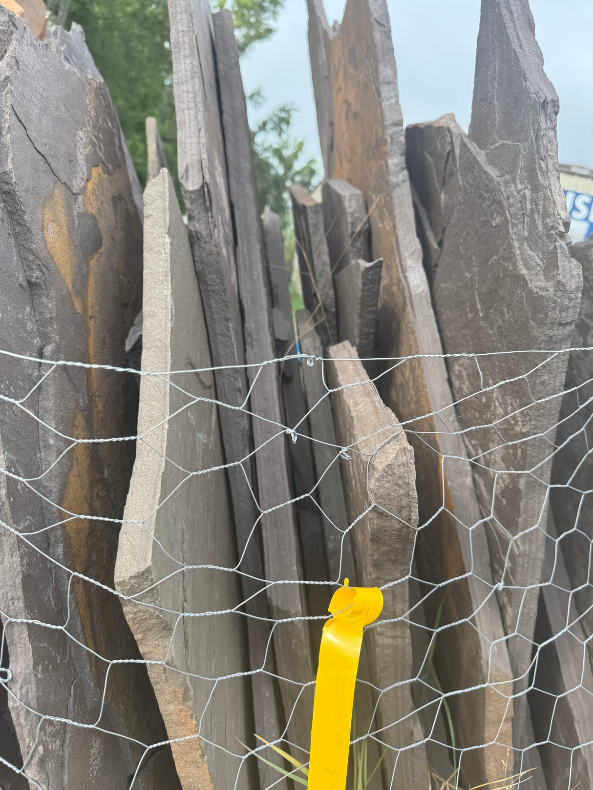 Stack of stone slabs with a yellow ribbon on a wire mesh