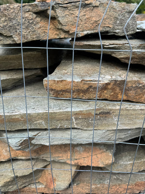 Stack of sea- mist flagstone slabs behind wire mesh