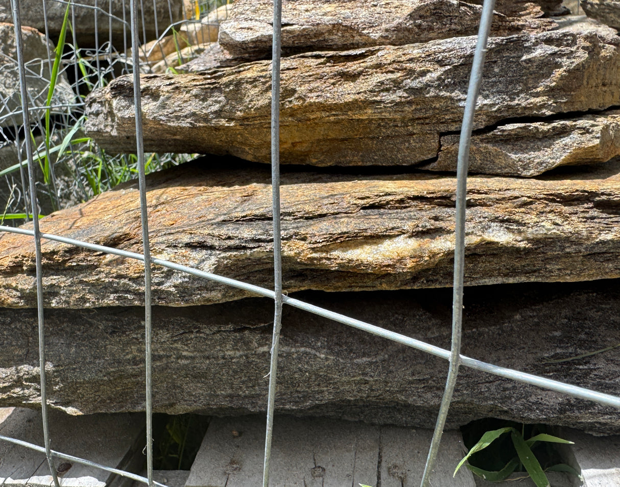 Stack of stone slabs with metal wire mesh in a garden setting