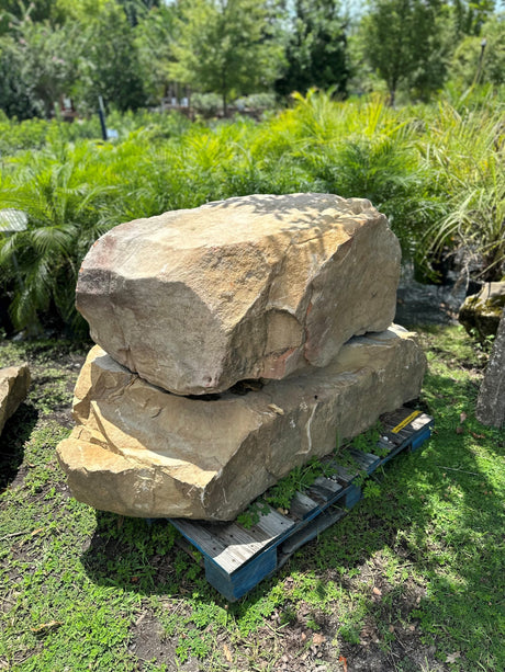 two large Tennessee boulders placed on a pallet in a garden setting